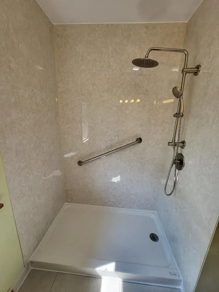Accessible shower with grab bar, rain showerhead, and handheld showerhead. White and beige tones.