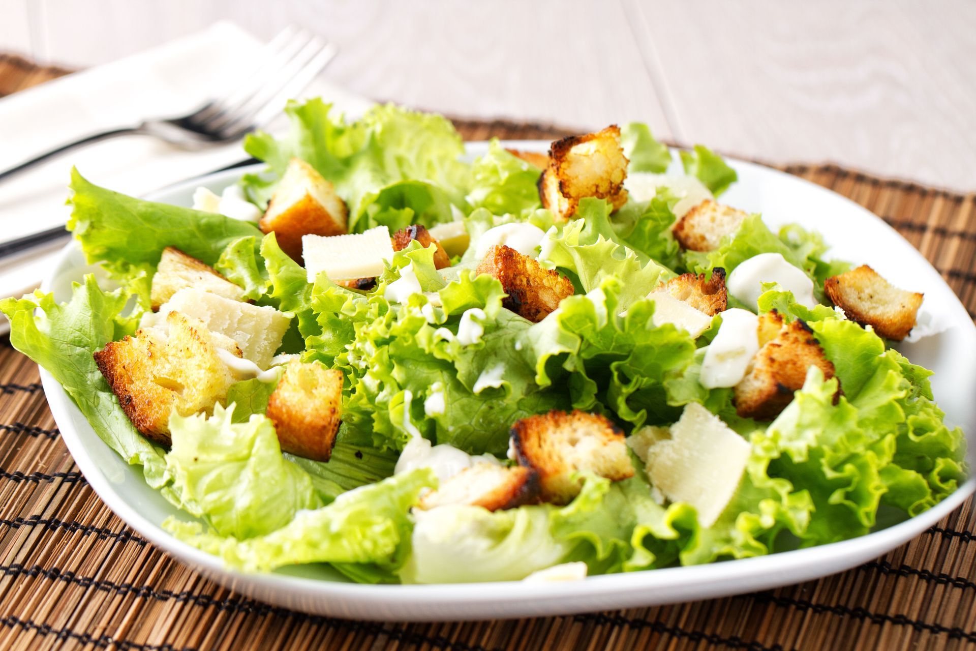 Caesar salad with lettuce, croutons, and grated cheese on a white plate
