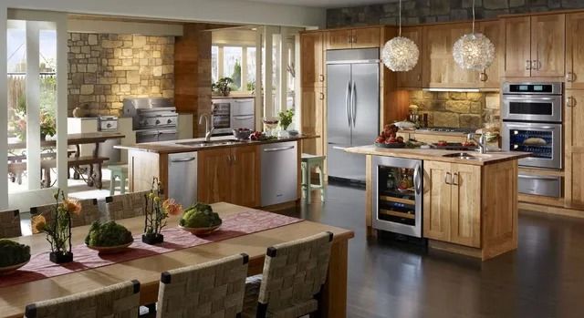 Modern kitchen with island dining table, stainless appliances, wood cabinets, and pendant lights