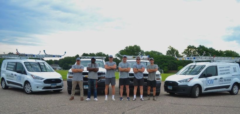 A group of men are standing next to a truck in front of a house.