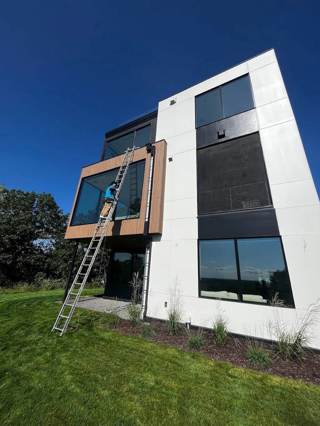 A man is standing on a ladder in front of a large building.