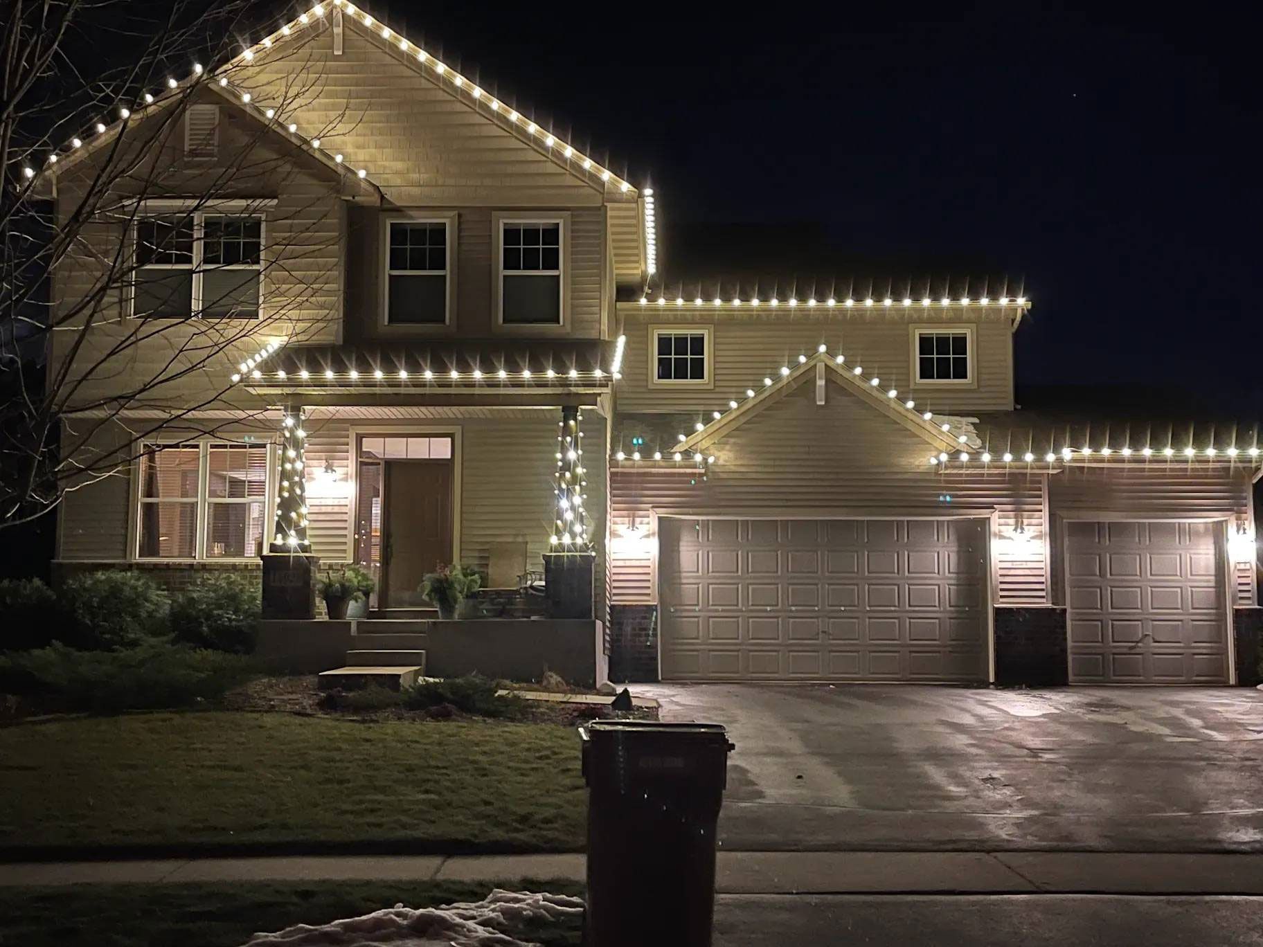 A house with christmas lights on it is lit up at night.