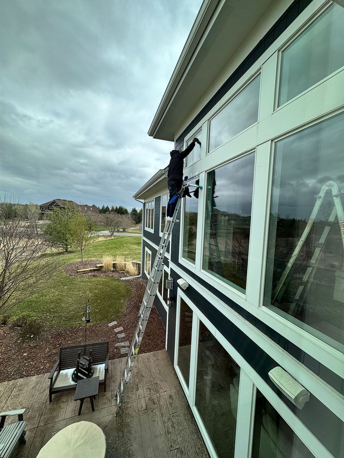 A man is cleaning the windows of a house on a ladder.