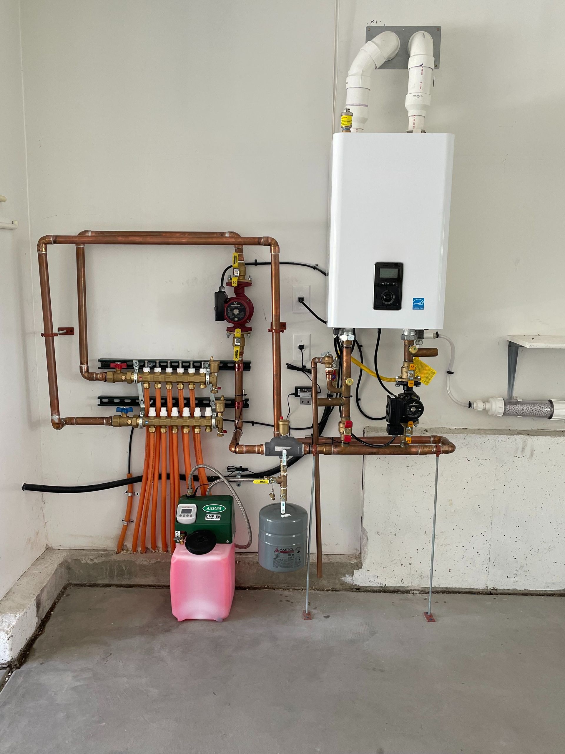 A room with a boiler and copper pipes on the wall.