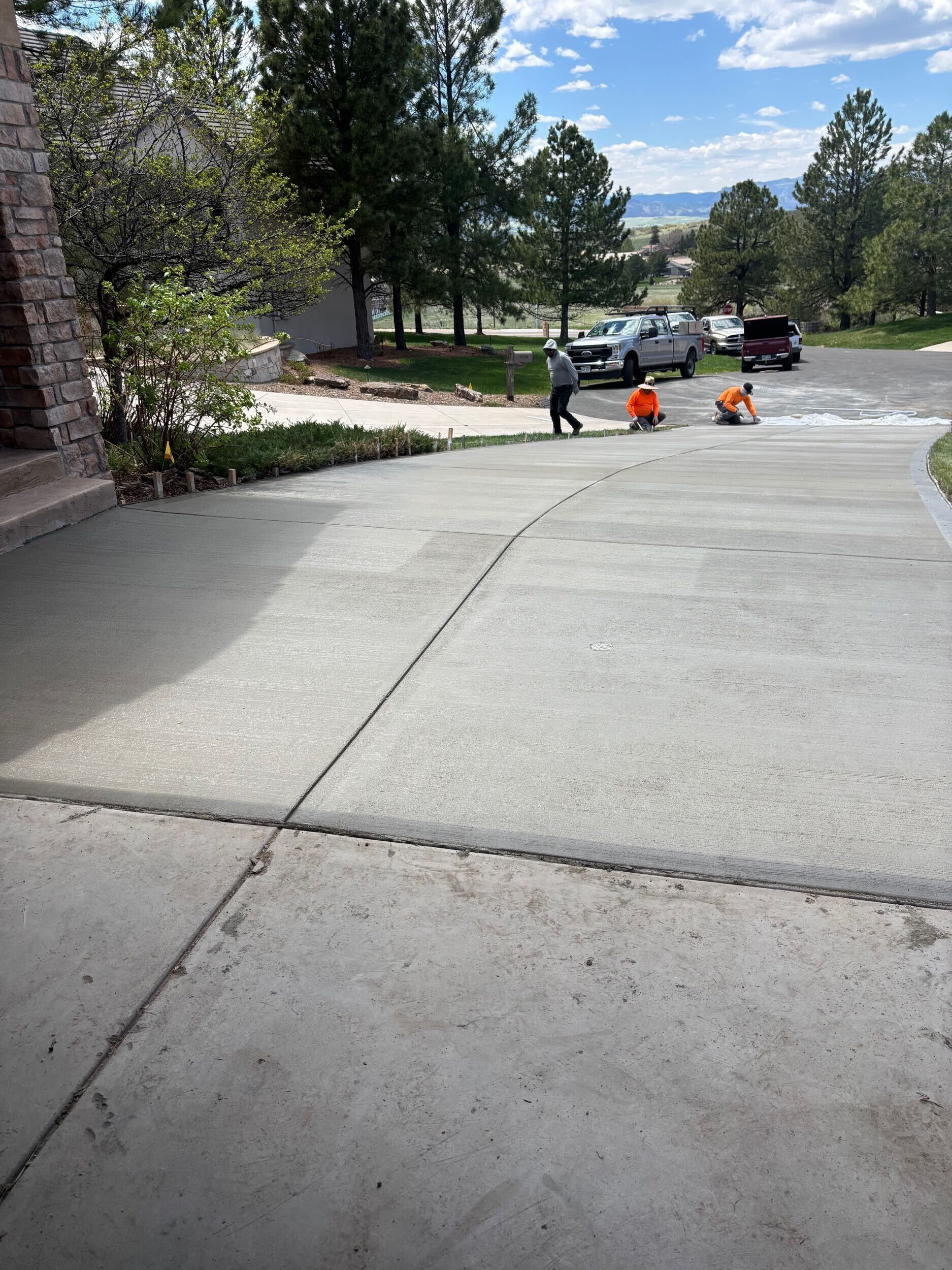 A group of people are working on a concrete driveway.