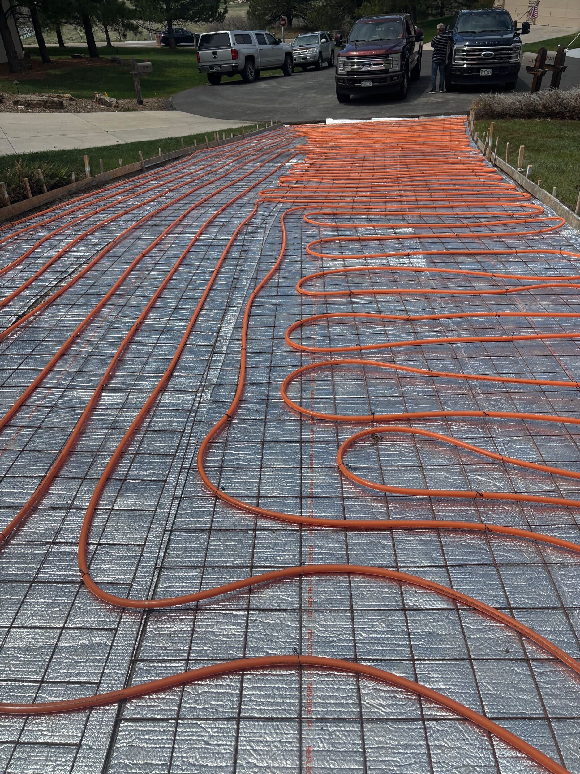A driveway with a lot of hose on it and cars parked in the background.