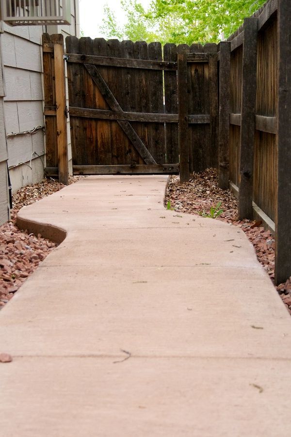 A concrete walkway leading to a wooden fence