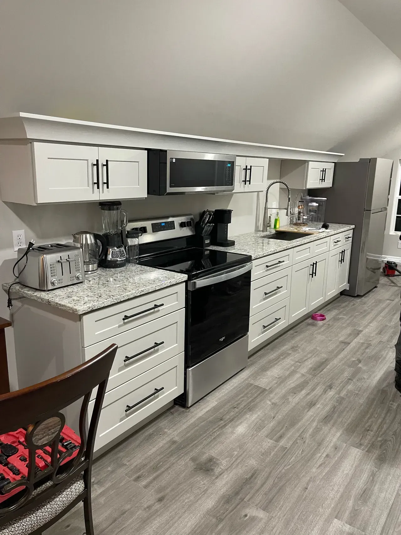 A kitchen with white cabinets , stainless steel appliances , and a refrigerator.