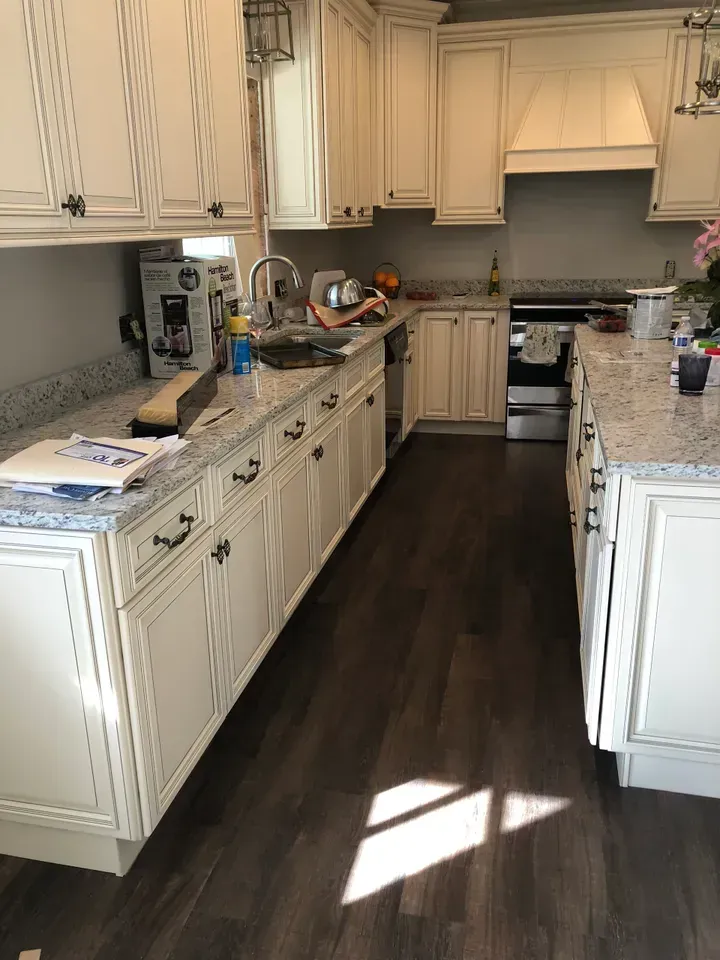 A kitchen with white cabinets and granite counter tops.