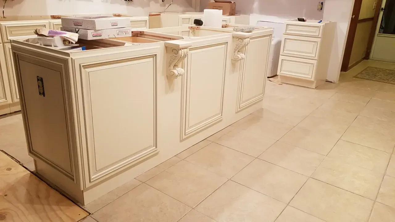 A kitchen island with white cabinets and a brick wall.
