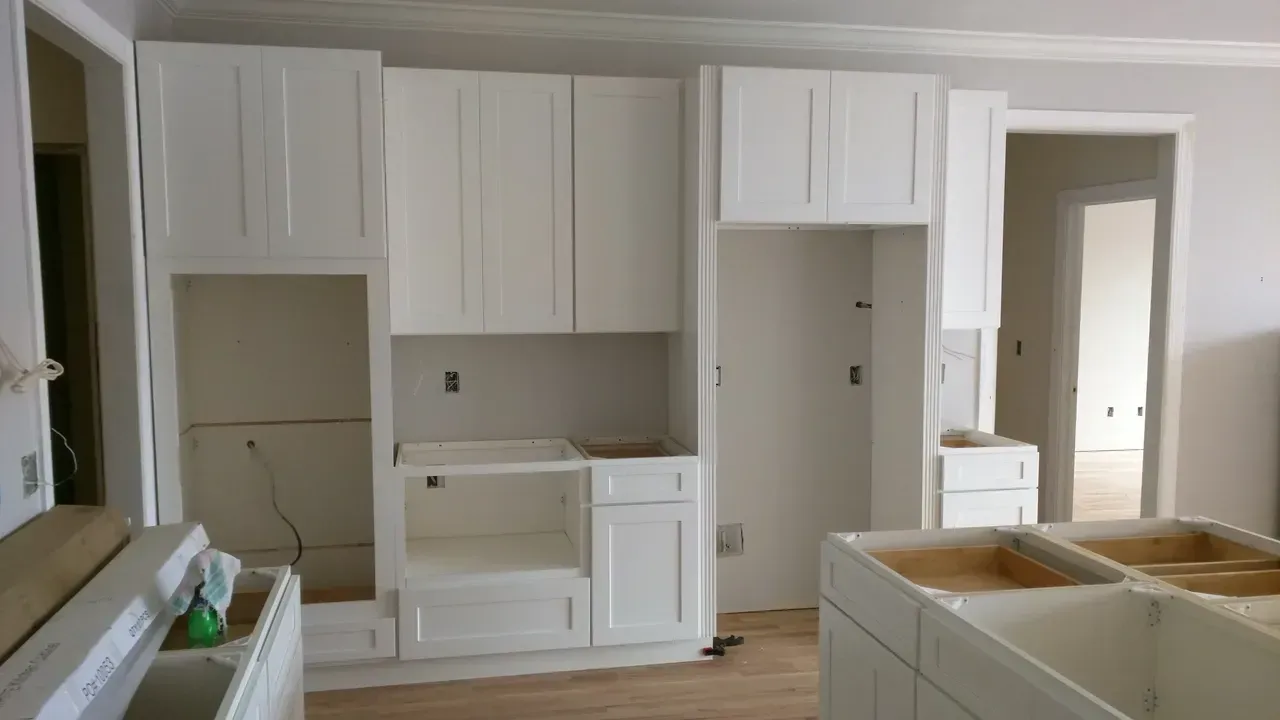A kitchen with white cabinets and a tiled floor is being remodeled.