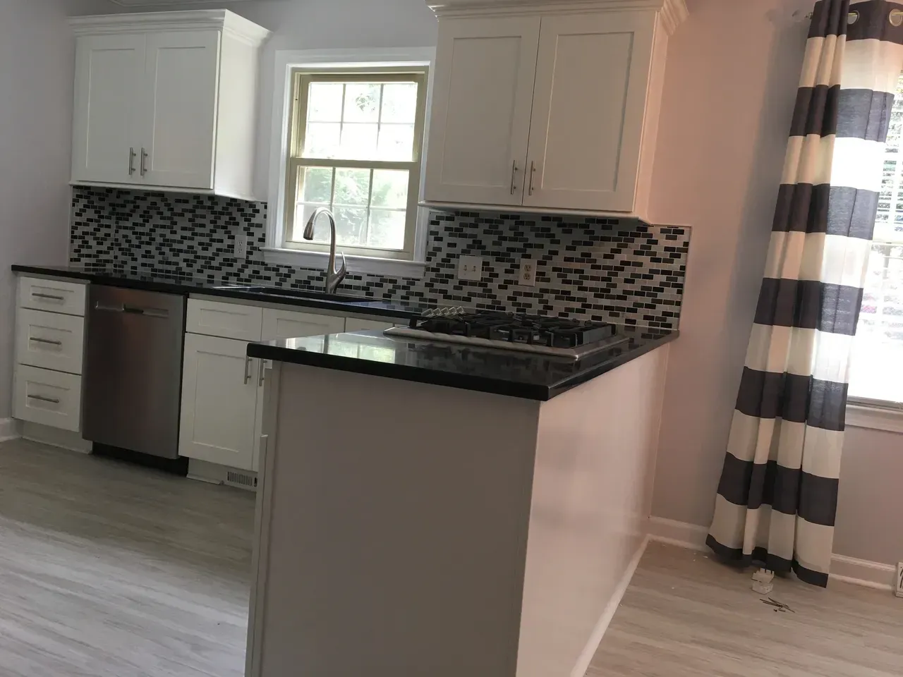 A kitchen with white cabinets and a black counter top