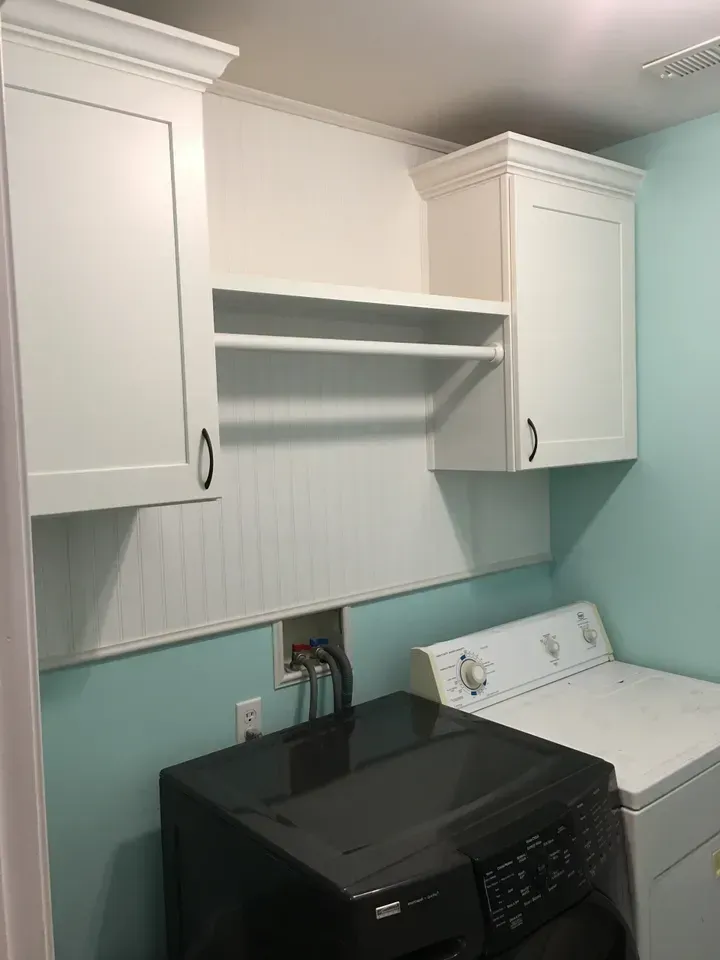 A laundry room with a washer and dryer and white cabinets.