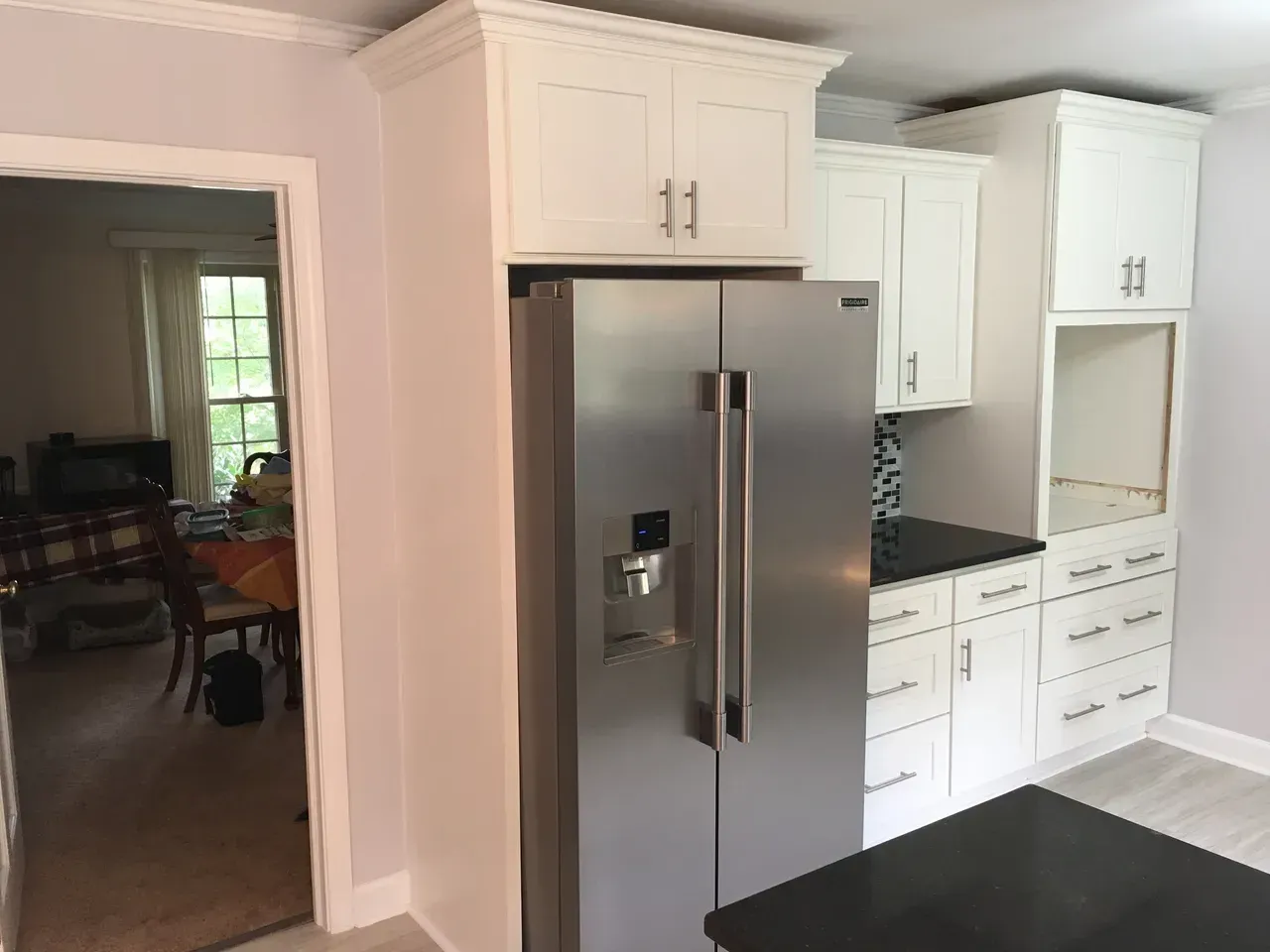 A kitchen with white cabinets and a stainless steel refrigerator.