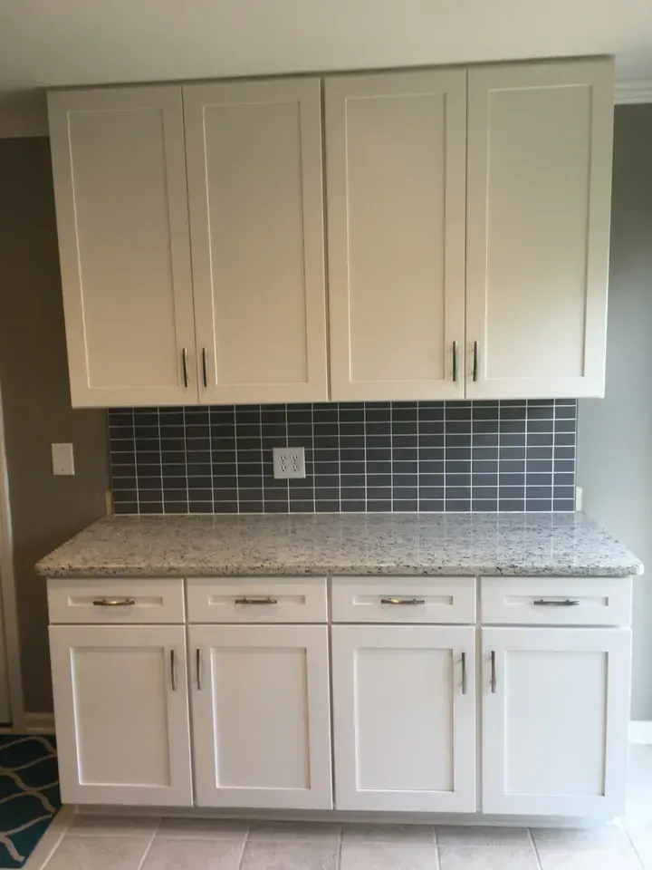 A kitchen with white cabinets and a granite counter top.
