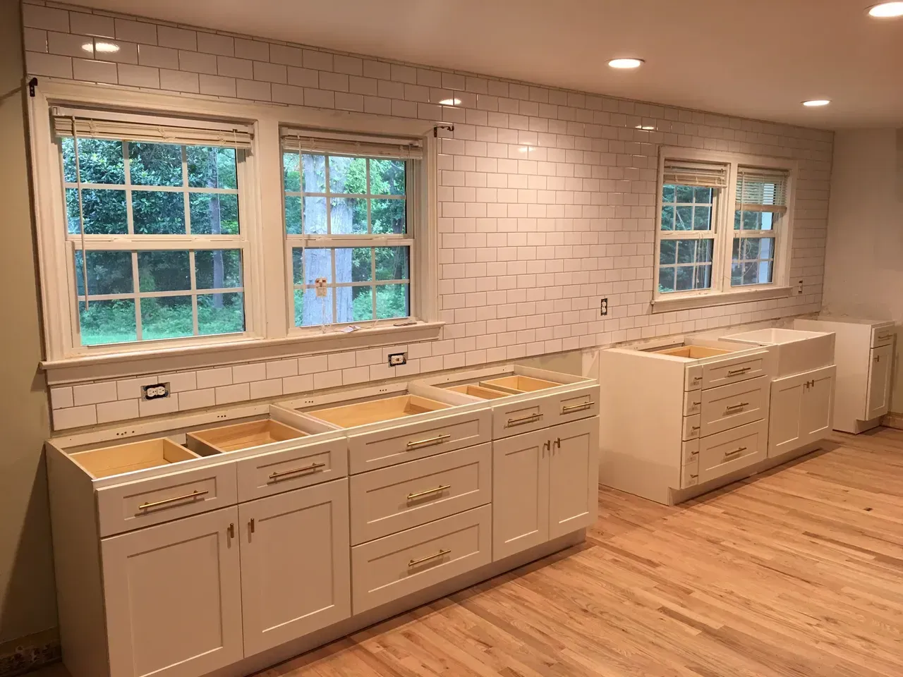A kitchen with white cabinets and hardwood floors is being remodeled.