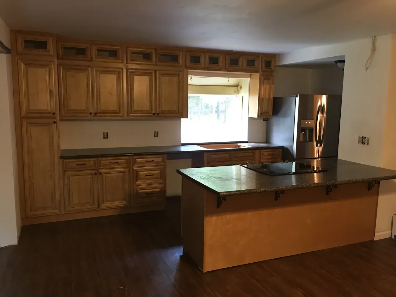 An empty kitchen with stainless steel appliances and wooden cabinets