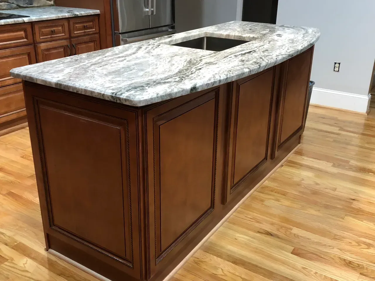 A kitchen island with a sink and granite counter top.