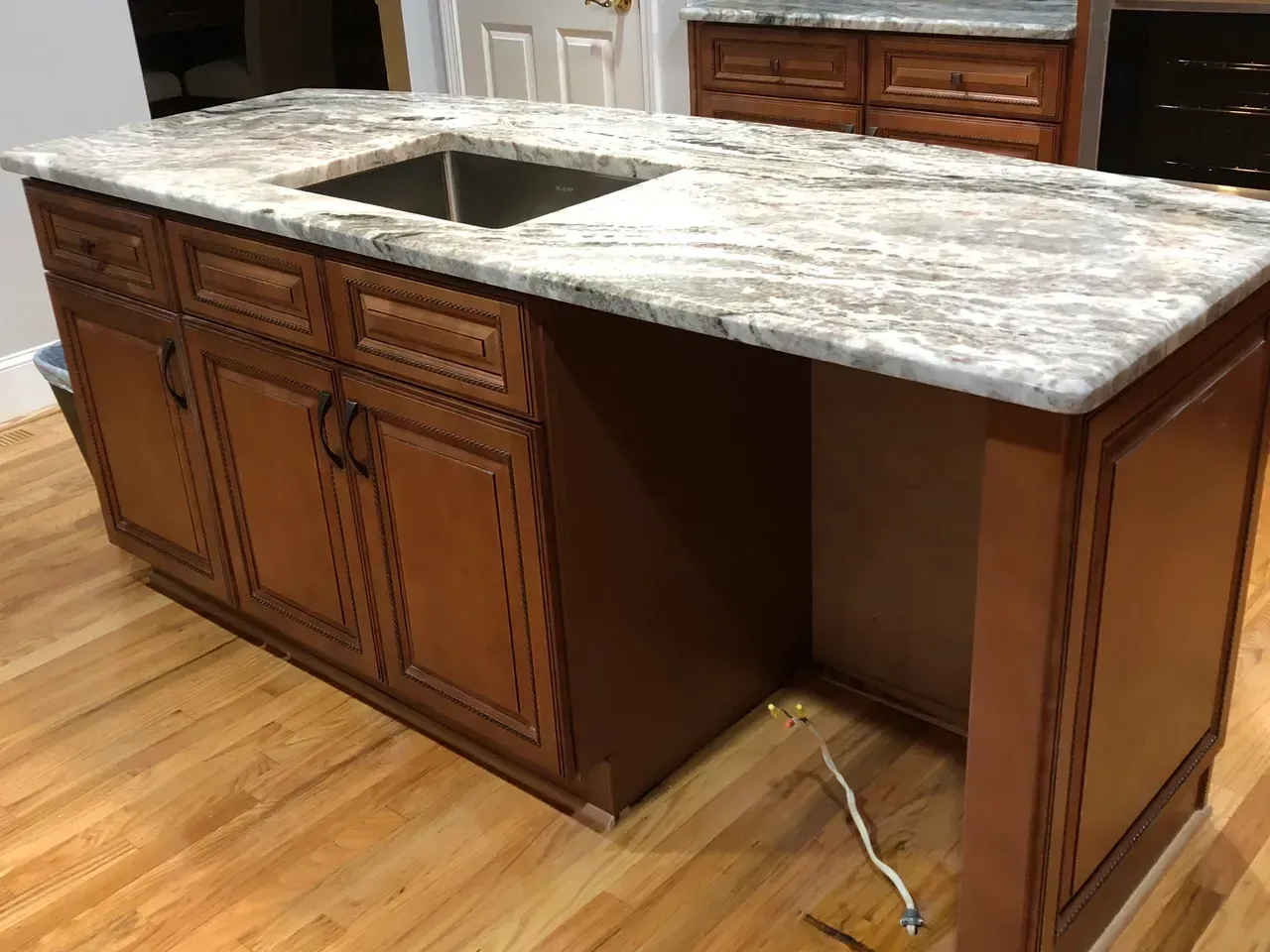 A kitchen island with a sink and granite counter top.