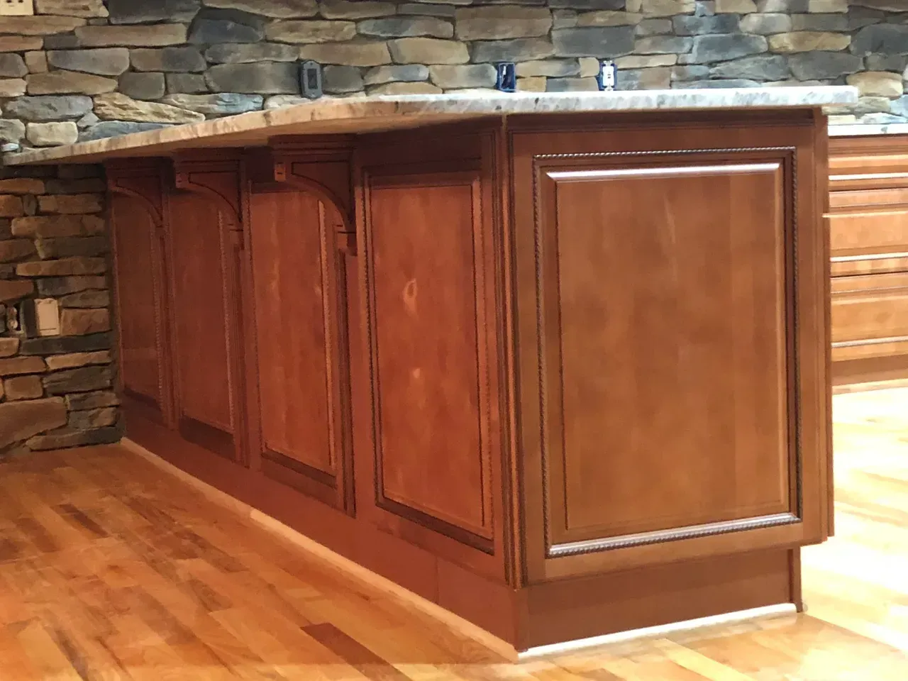 A kitchen with wooden cabinets and a stone wall.