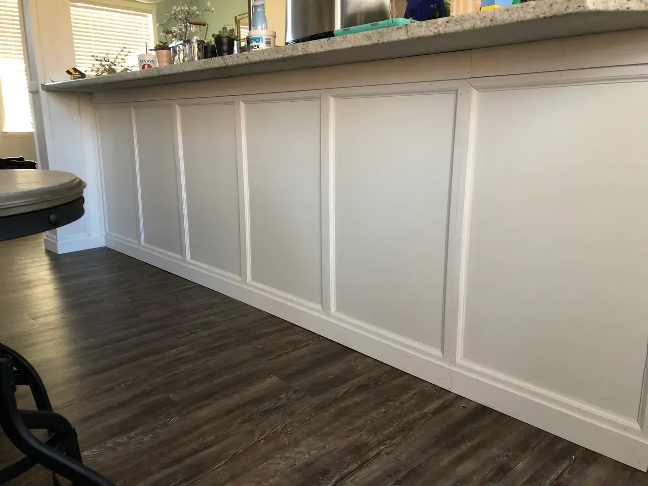 A kitchen counter with white cabinets and a wooden floor.