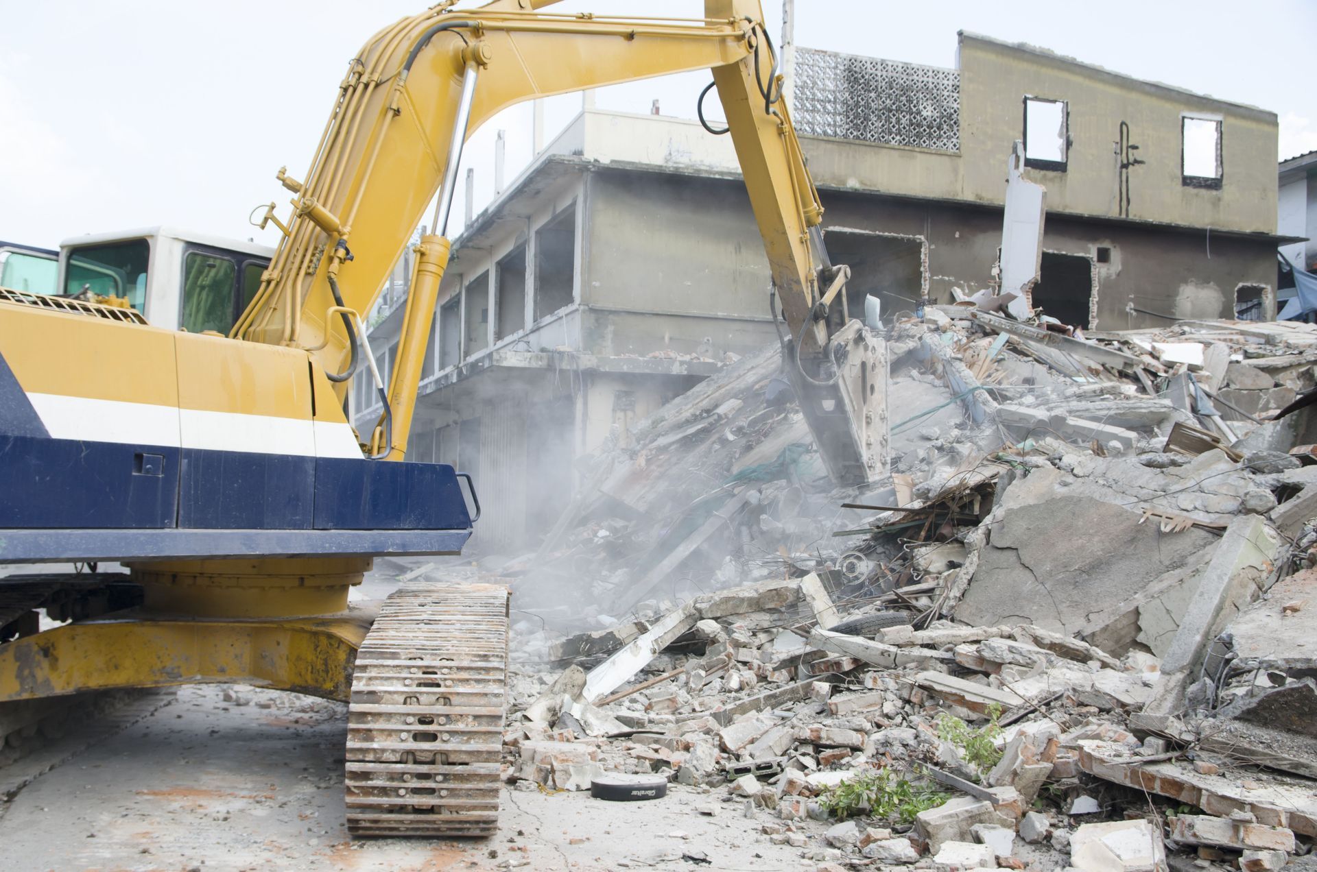 A large yellow excavator is demolishing a building.