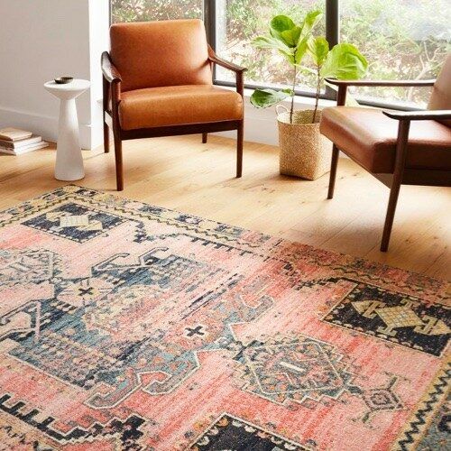 A living room with two chairs and a rug on the floor.