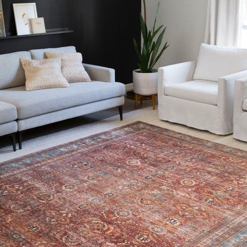 A living room with a couch , chair , and rug.