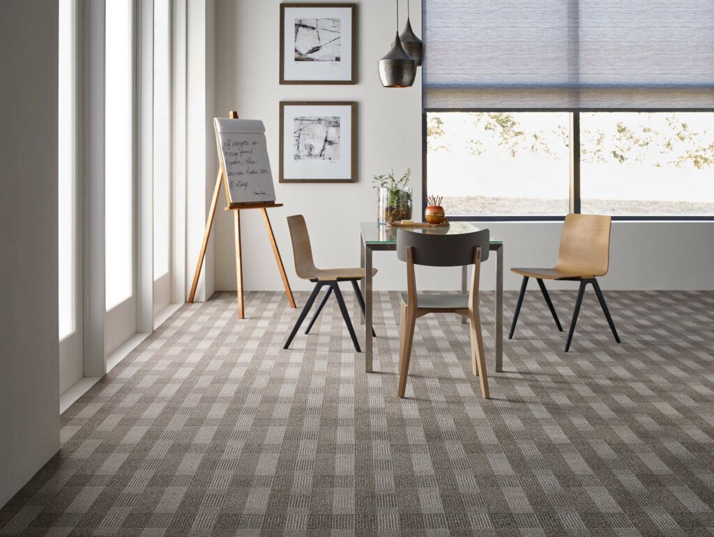 A room with a table and chairs and a carpeted floor.