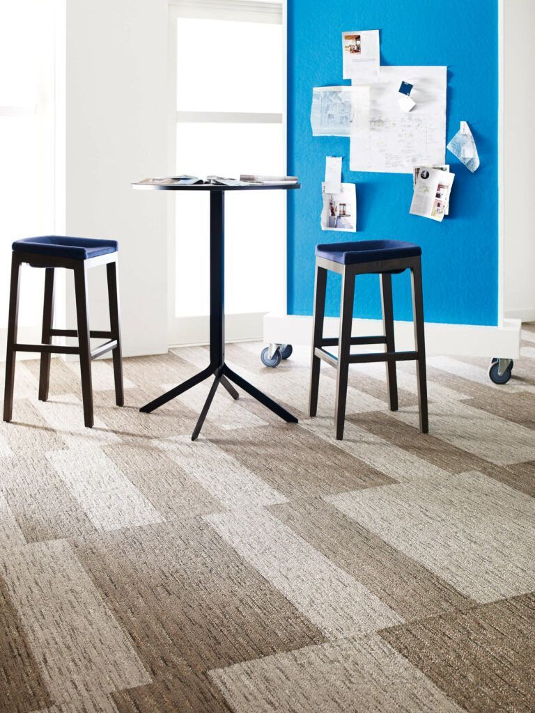 A room with a table and stools in front of a blue wall.