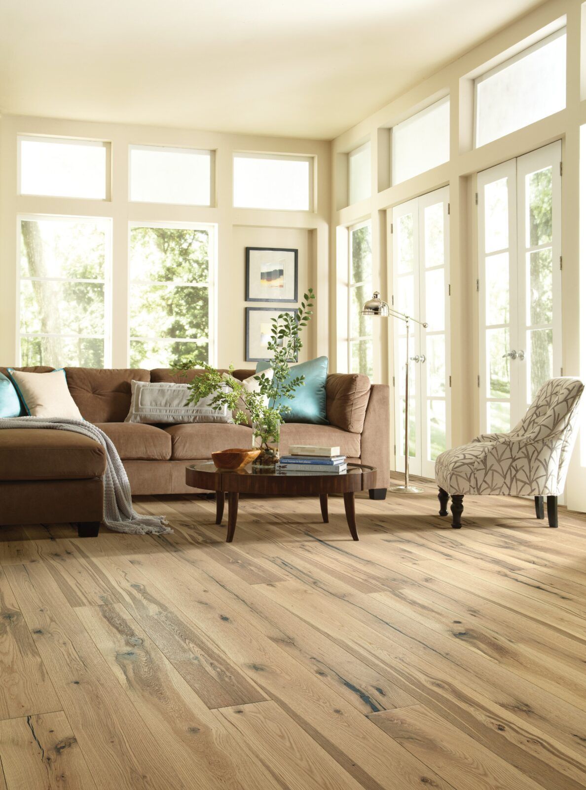 A living room with hardwood floors , a couch , chair , coffee table and lots of windows.
