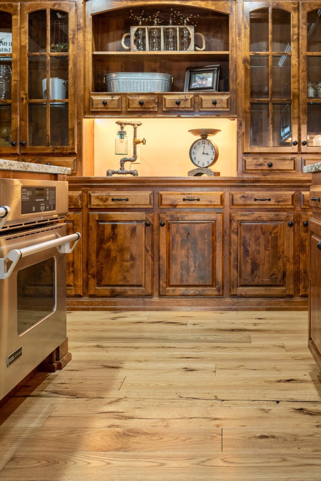 A kitchen with wooden cabinets , a stove , a scale and a hutch.