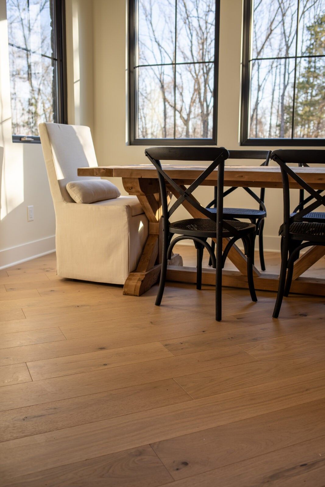 A dining room with a wooden table and chairs and a wooden floor.