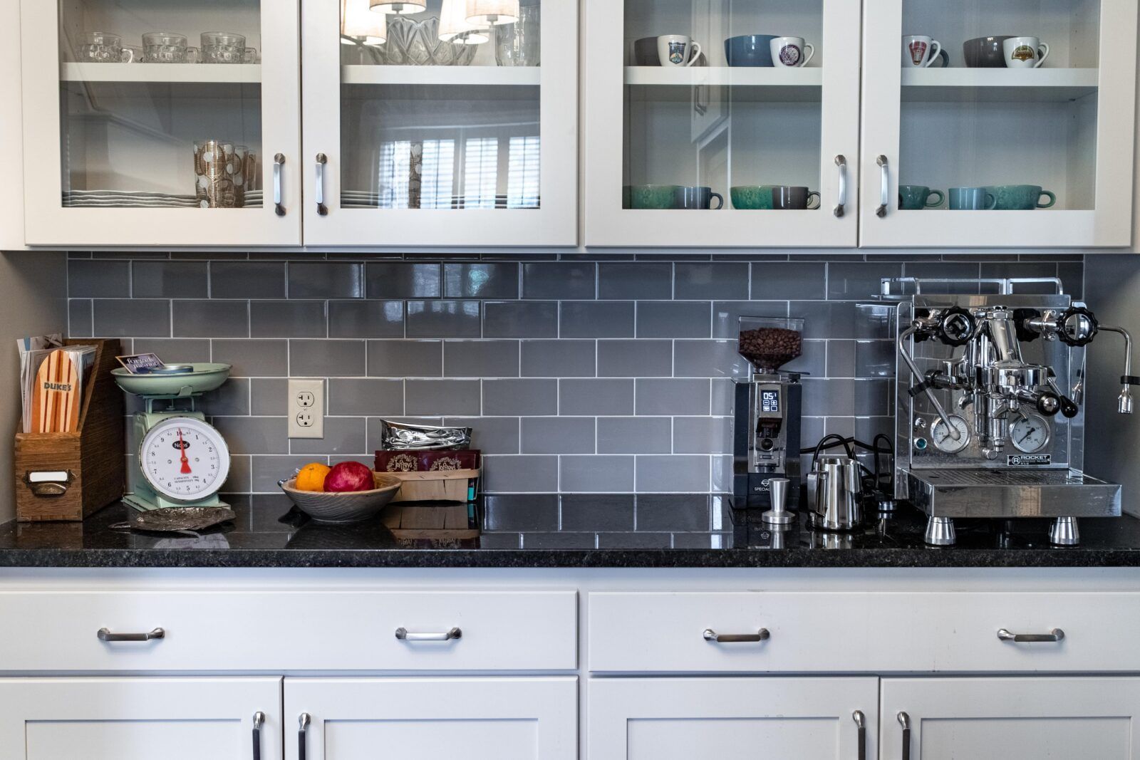 A kitchen with white cabinets and a scale on the counter