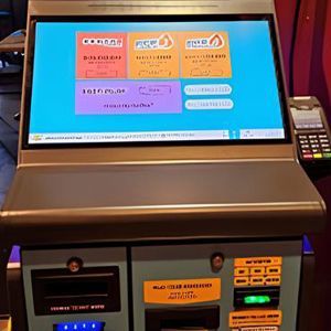 Lottery ticket vending machine with a bright screen showing lottery options.