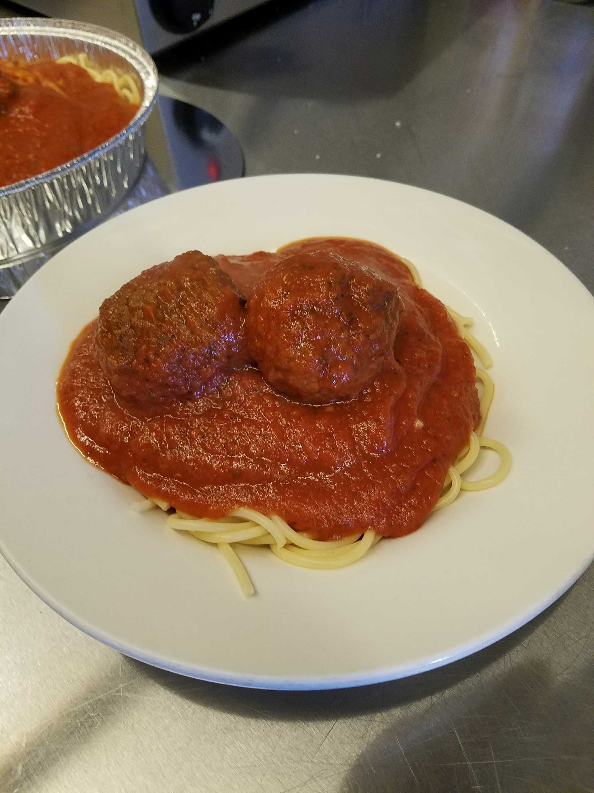 spaghetti and meatballs covered in red sauce on a white plate