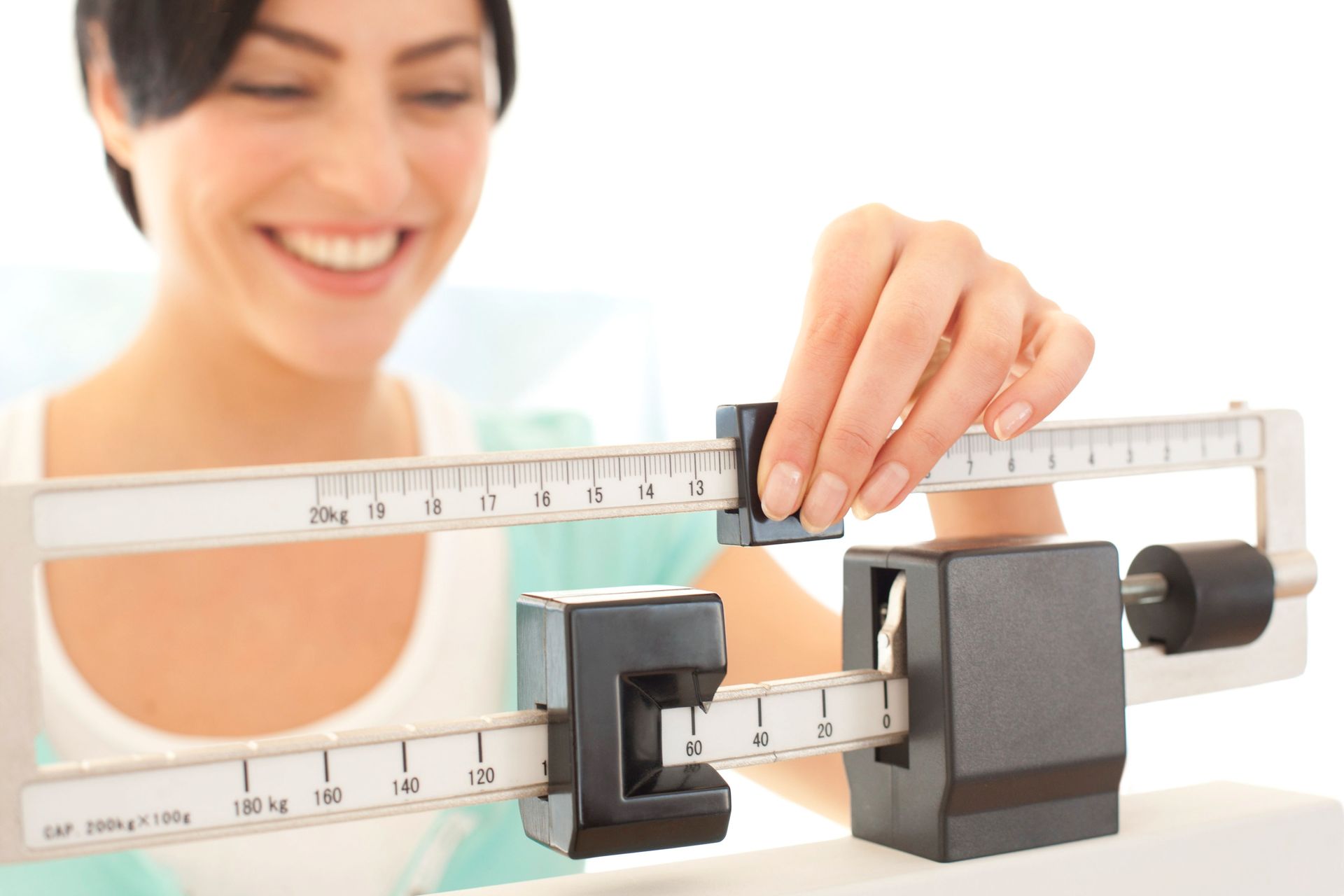Woman adjusting a balance beam scale, smiling.