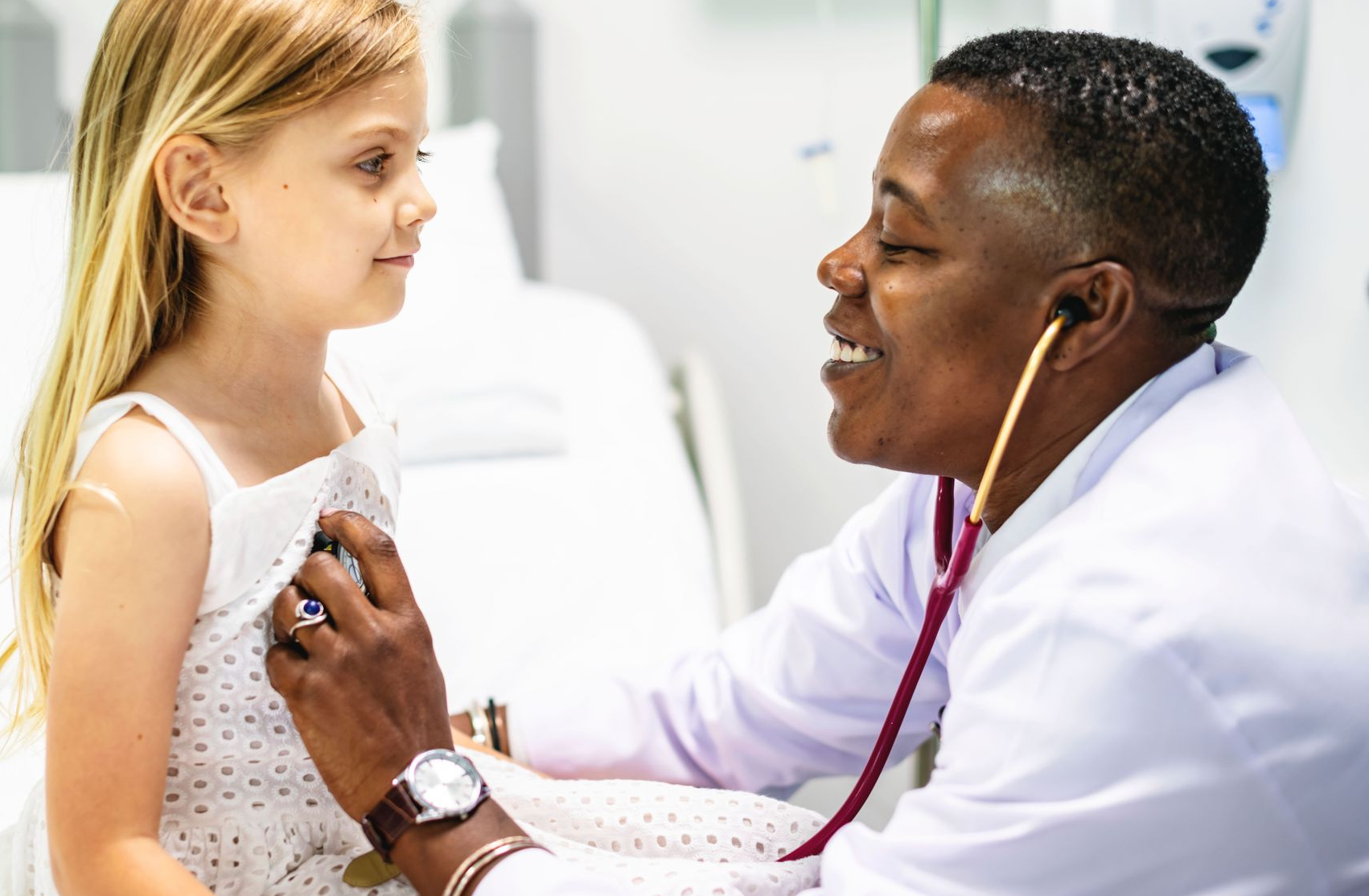 Doctor using a stethoscope on a young child's chest in a medical setting