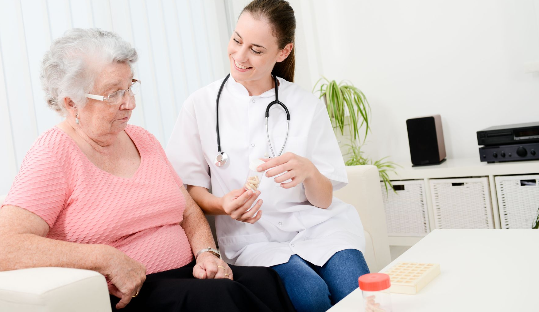 A medical professional shows pills to an elderly patient