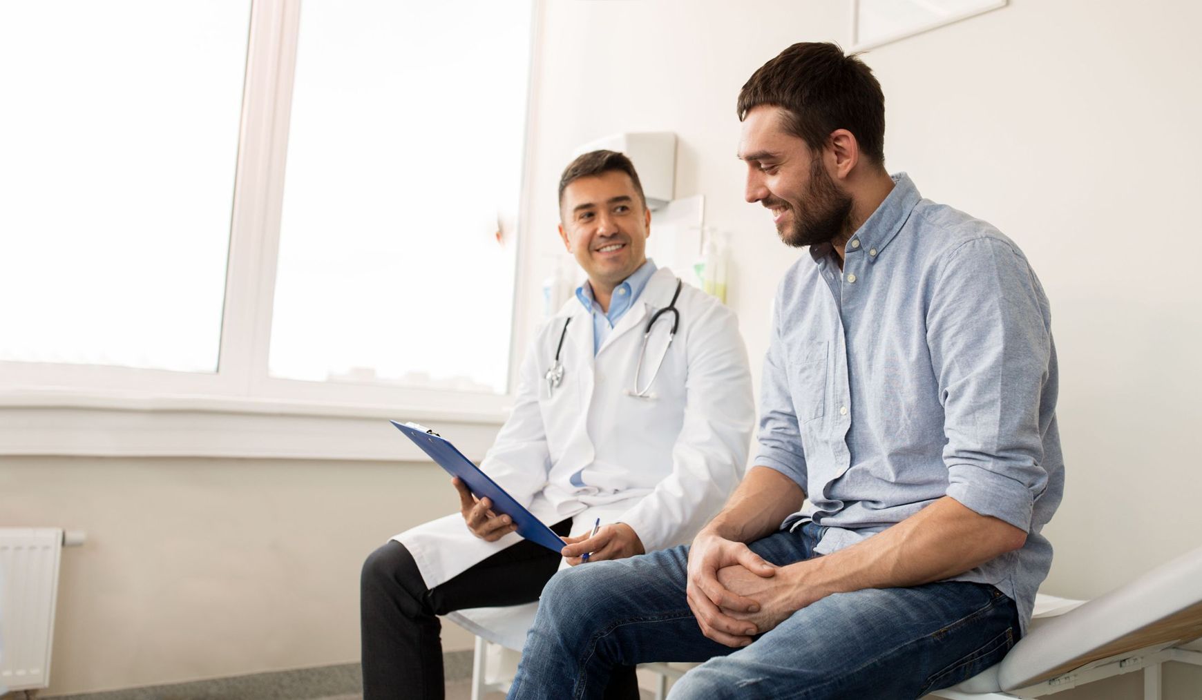 Man in blue shirt smiles at doctor in white coat