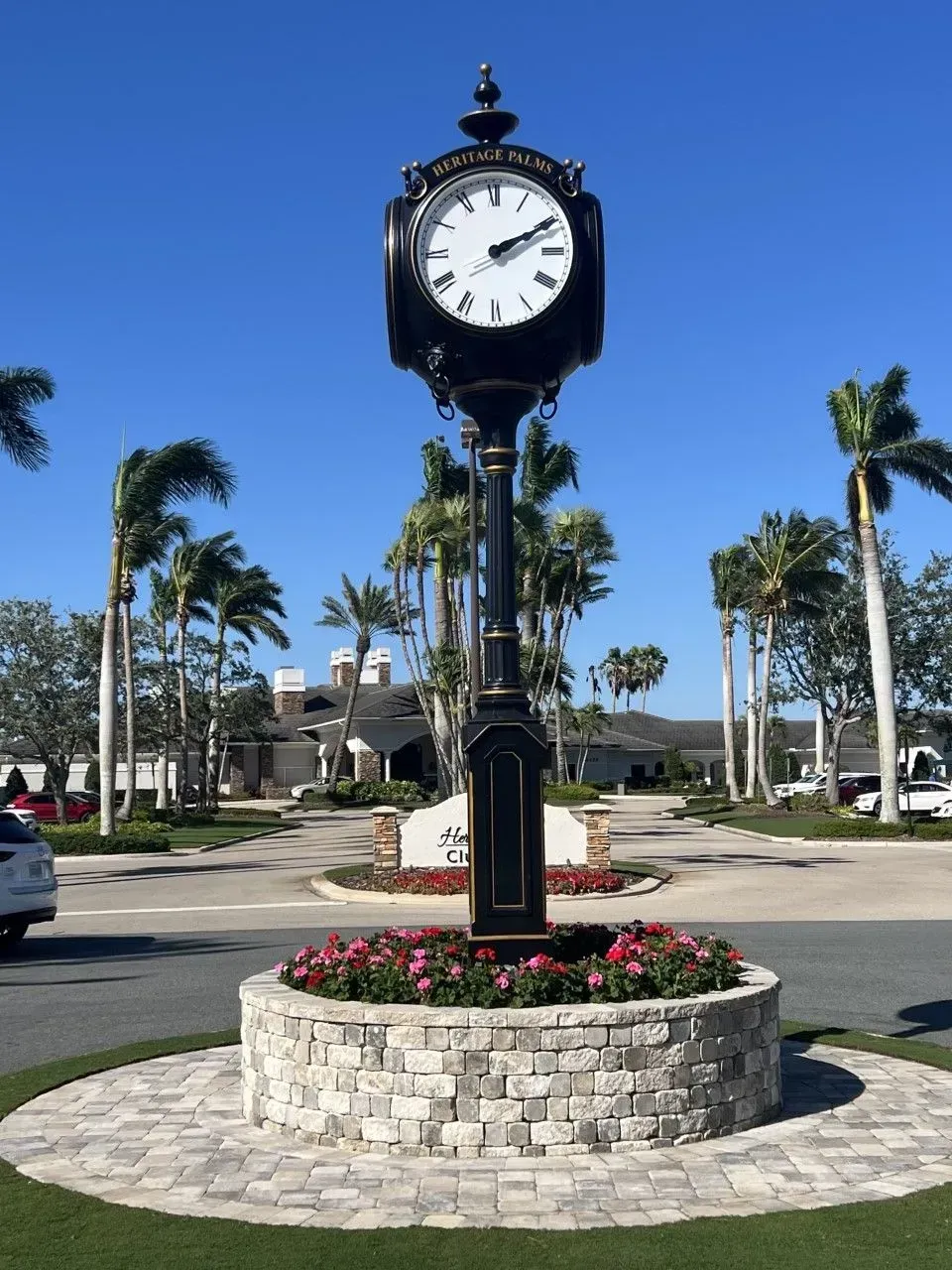 A large clock stands in the middle of a parking lot