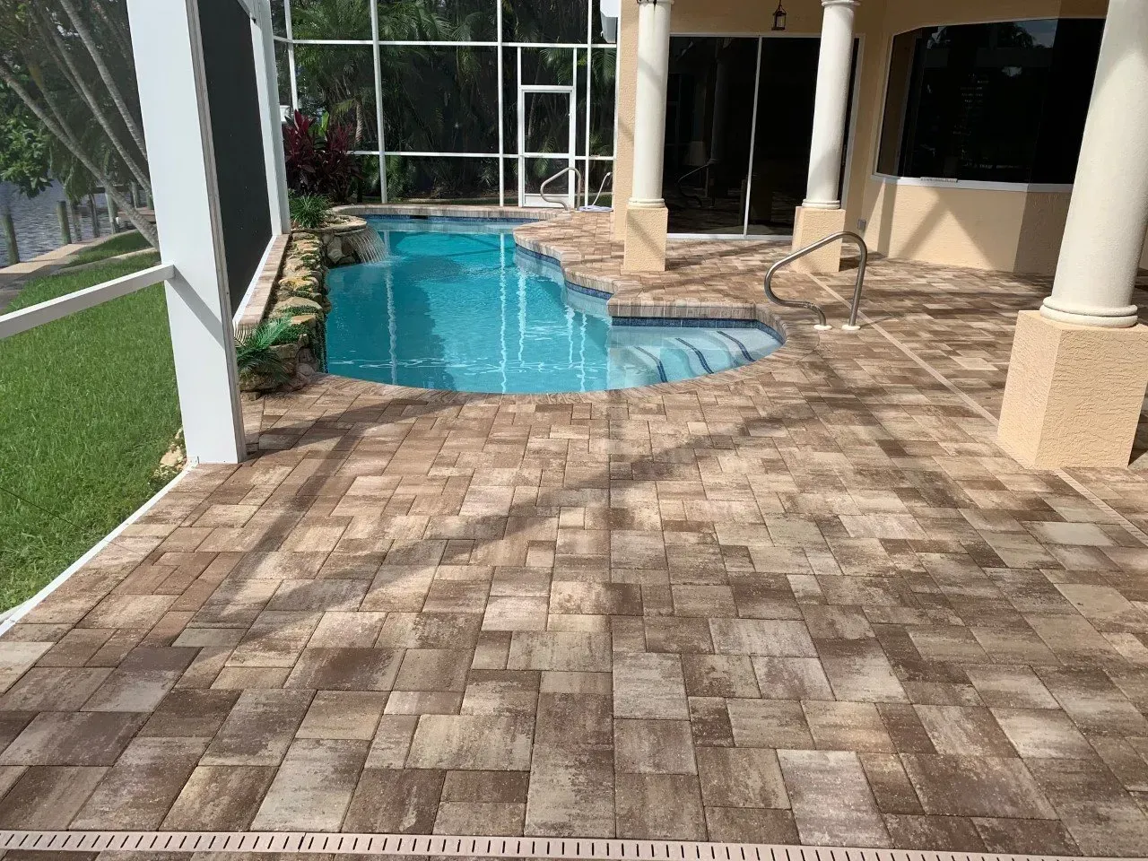 A patio with a swimming pool in the backyard of a house.