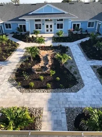 A large blue house with a lush green garden in front of it.