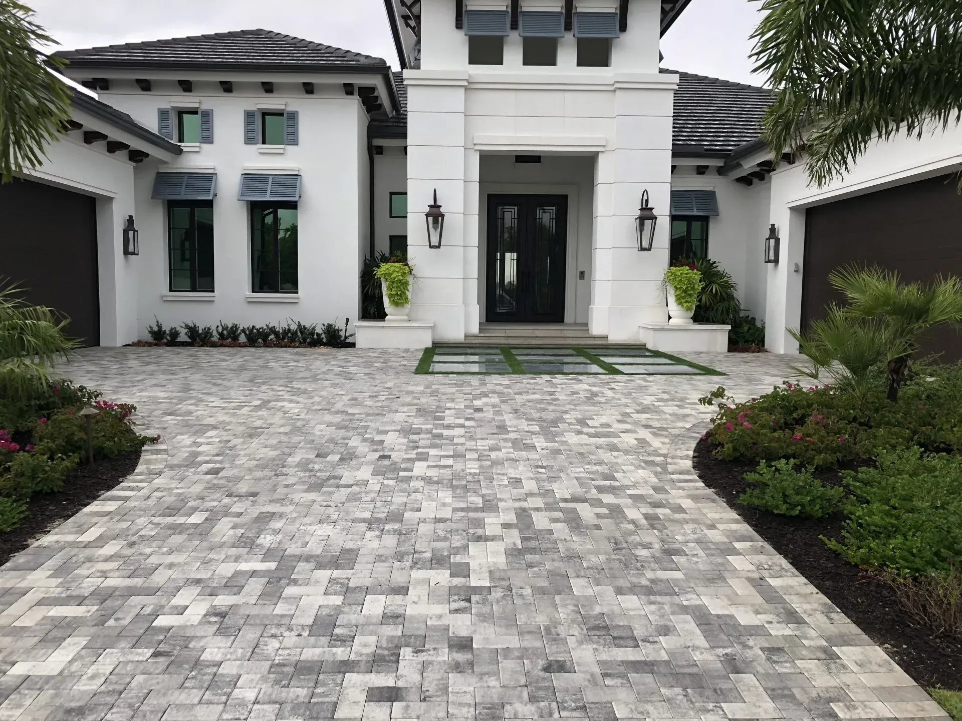 A large white house with a brick driveway leading to it.