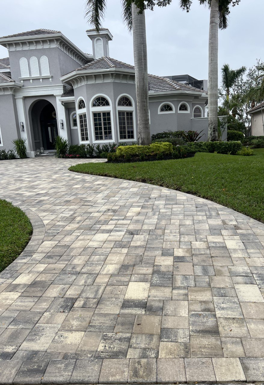 A large house with a brick driveway leading to it.