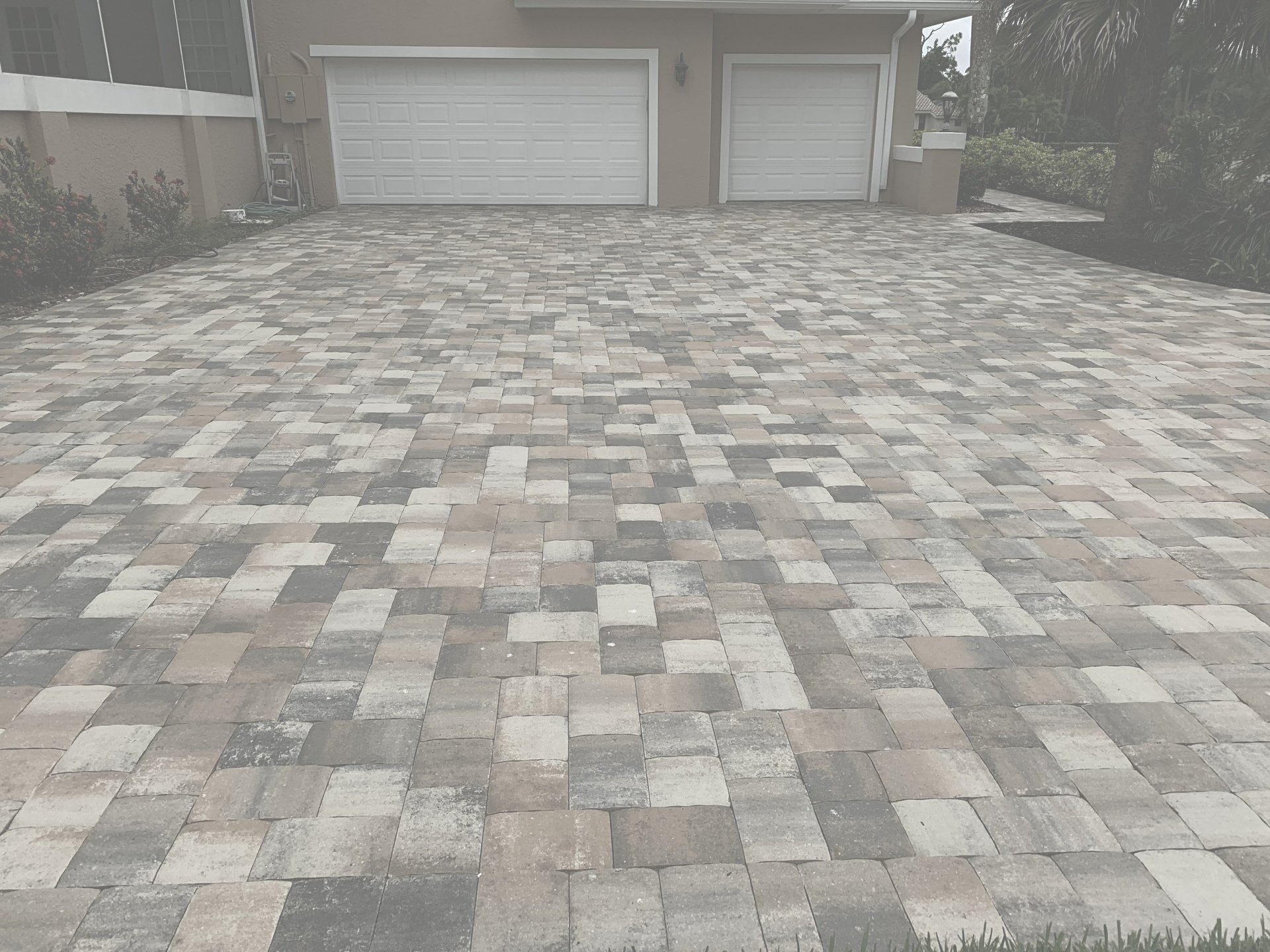 A black and white photo of a brick driveway leading to a garage.