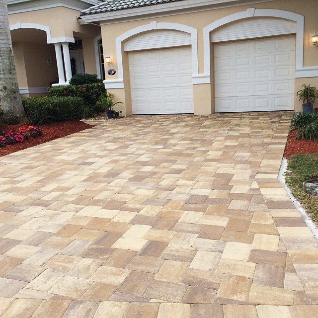 A driveway in front of a house with two garage doors