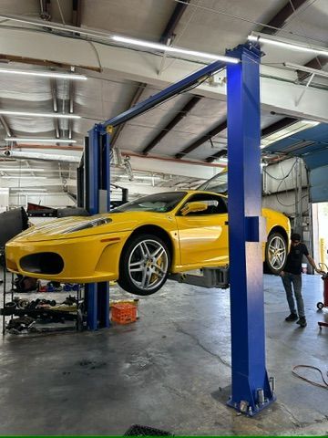 A yellow sports car is on a lift in a garage.