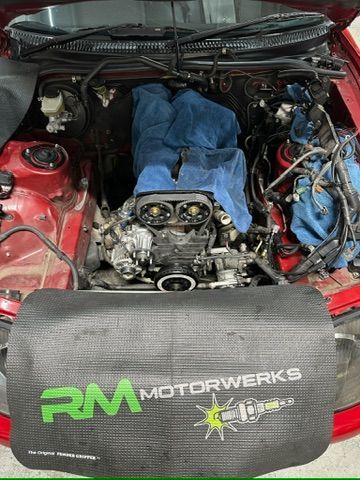 The engine of a red car is being worked on.