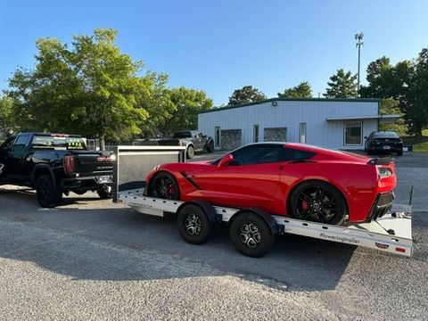 A red sports car is being towed on a trailer.